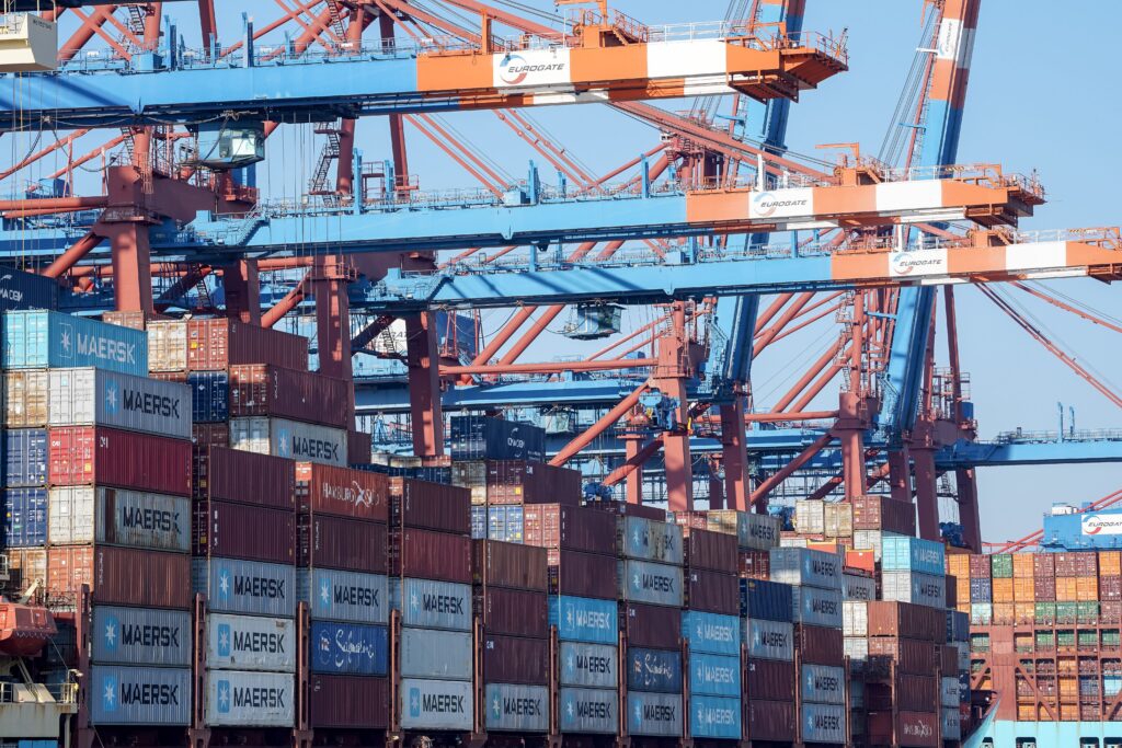 A bustling view of the Hamburg port showing cranes and stacked shipping containers.